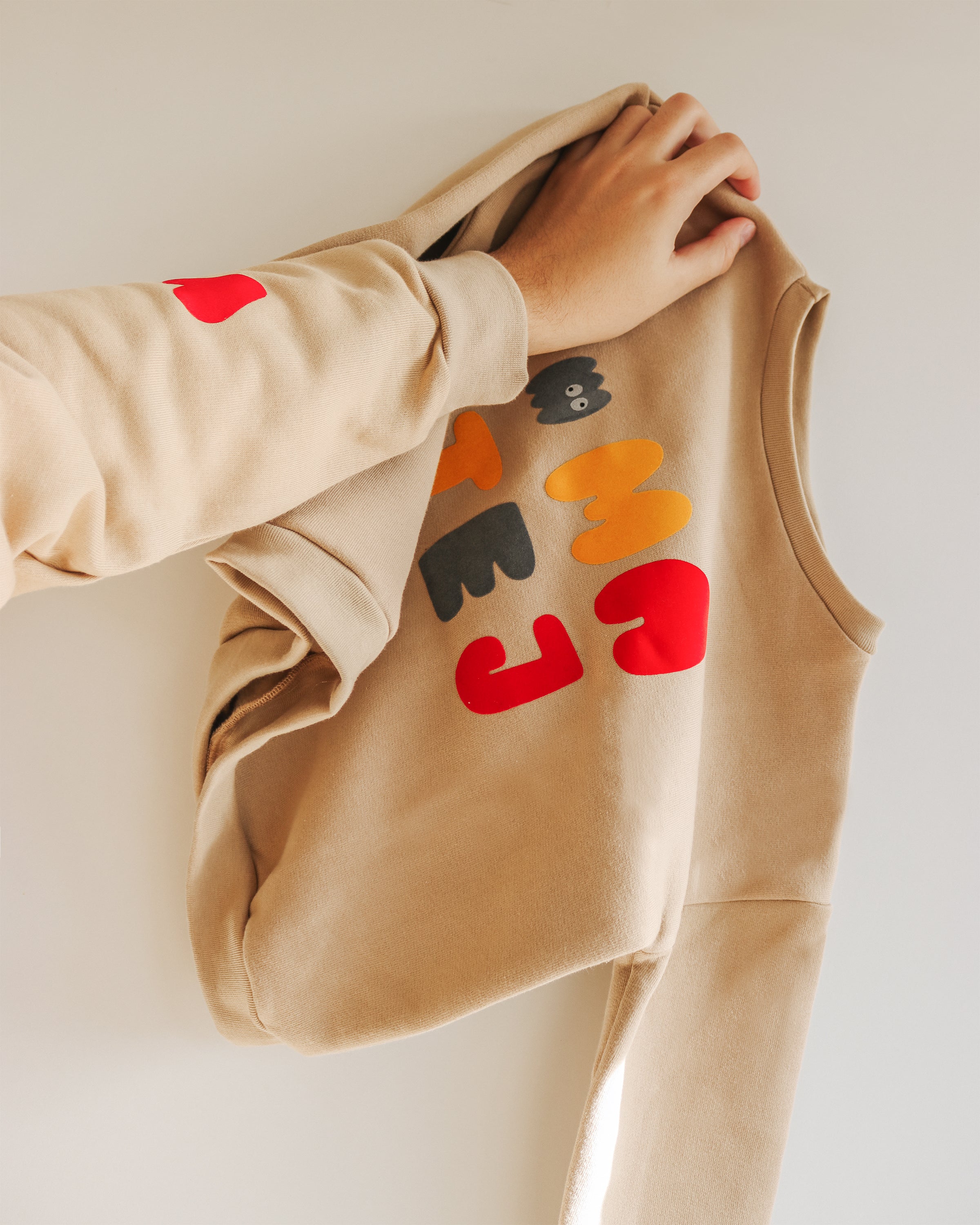 hand is holding up a vibrant and personalized kids' sweatshirt. 